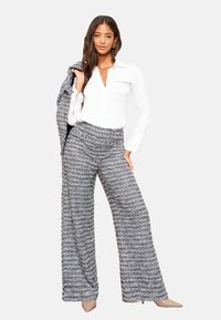 Hallid ja valged triibulised laia säärega püksid, millel on lõdvestunud istuvus, kõrge vöökoht ja tekstuurse kangaga. Sobivad kanda valge nööpidega särgiga.