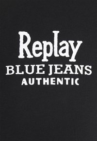 Biały tekst „Replay Blue Jeans Authentic” na czarnym materiale, wyśrodkowany i ułożony w trzech linijkach z różnymi czcionkami i rozmiarami.