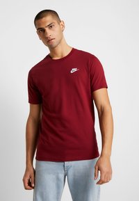 Burgundské tričko Nike vyrobené z bavlny, s okrúhlym výstrihom, krátkymi rukávmi a malým bielym logom na ľavej hrudi.