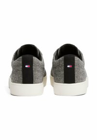 Teksturowane szare sneakersy z czarnymi akcentami i białą podeszwą, z małym logo w kolorach czerwonym, białym i niebieskim na pięcie.