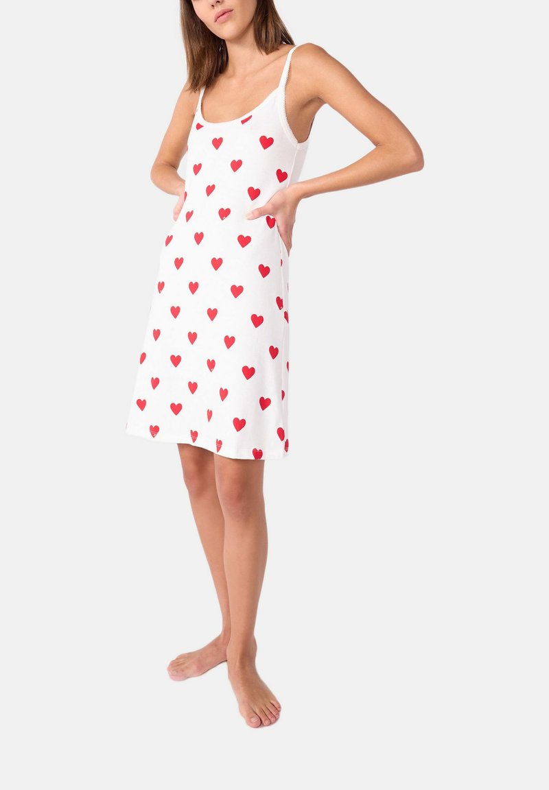 Abito bianco senza maniche con un motivo di cuori rossi, realizzato in tessuto morbido, con una vestibilità comoda e tasche laterali.