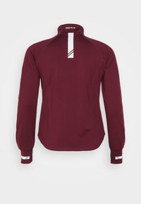 Maglietta sportiva a maniche lunghe color bordeaux con colletto alto e dettagli bianchi. Presenta un design sportivo e un tessuto testurizzato, con cuciture decorate sui bordi.