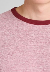 Triko s krátkým rukávem a kulatým výstřihem z jasně růžové látky s texturovaným povrchem, s kontrastním vínovým ribbed výstřihem.
