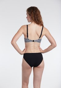 Bikini bianco e nero con un motivo geometrico sulla parte superiore, spalline regolabili e uno slip alto nero a tinta unita.