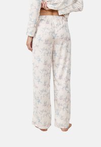 Pantalones de pijama ligeros de color crema con un patrón caprichoso de gatos y cintas en azul y rosa, con cintura elástica.