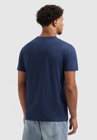 Navyblauwe katoenen t-shirt met korte mouwen, ronde halslijn en een gladde textuur, gedragen met lichtblauwe jeans.