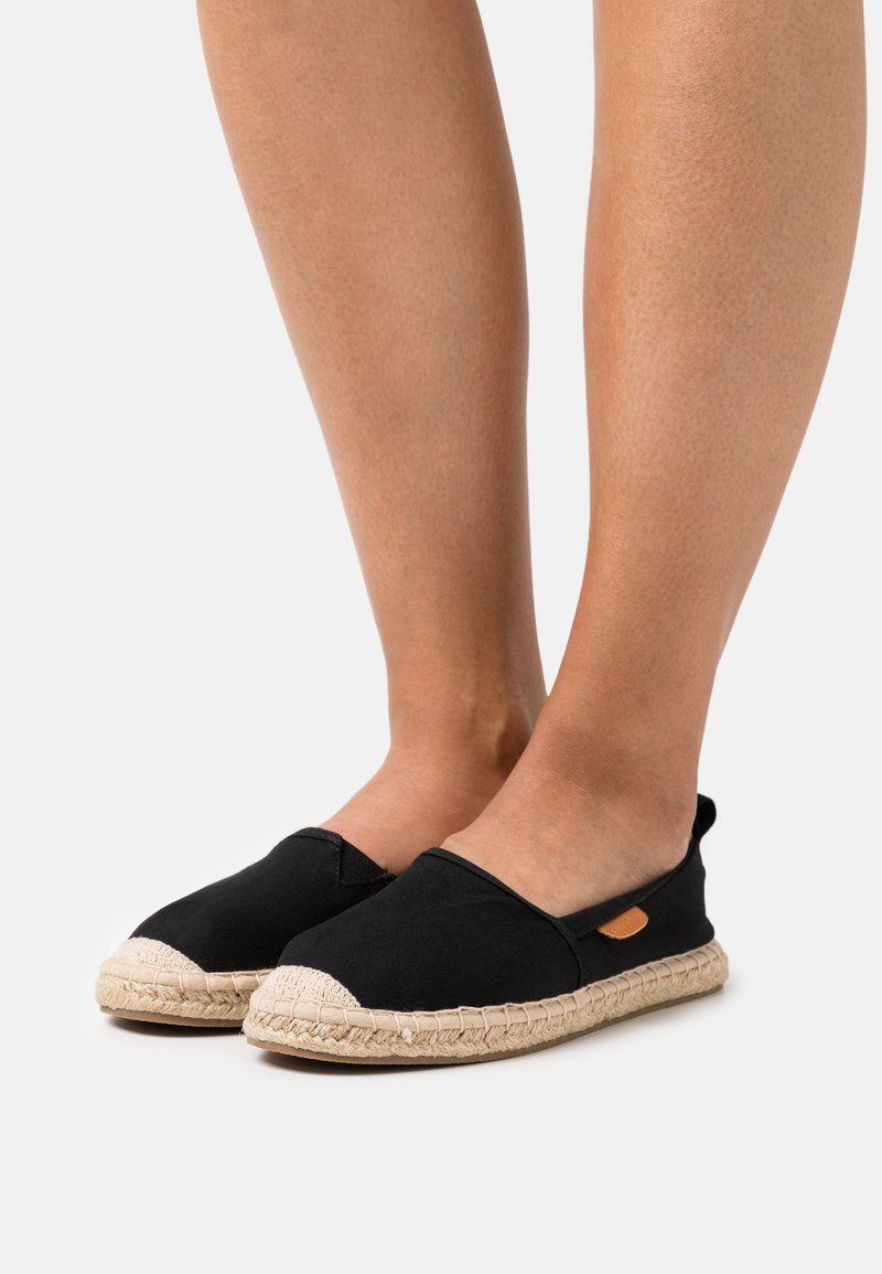Svarta kanvas slip-on skor med en flätad jutesula och släta gummidetaljer. Rund tå och minimal detaljer.