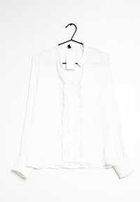 Weiße Bluse mit langen Ärmeln aus leichtem Stoff, mit einer gerafften Blende vorne, Knopfverschluss und einem befestigten Anhänger.