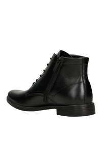 Stivali ankle in pelle nera con finitura liscia, dotati di cerniera laterale, lacci frontali e punta rotonda. Suola in gomma per una migliore aderenza.