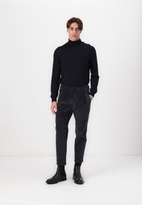 Námornícky rolák s dlhými rukávmi skombinovaný s nohavicami z antracitového jemného manžestru. Čierne kožené členkové čižmy, minimalistický dizajn, hladká textura.