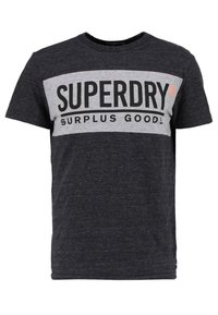 Černé a šedé tričko s krátkým rukávem a kulatým výstřihem, s výrazným potiskem "SUPERDRY SURPLUS GOODS" přes hrudník.