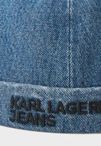 Denim cap with blue fabric, featuring a structured shape and a black embroidered logo reading "KARL LAGERFELD JEANS" along the brim.