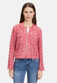 Czerwony żakiet z tweedu o teksturowanym wykończeniu, zapinany na zamek, z dwiema kieszeniami z przodu i postrzępionymi brzegami. Długie rękawy i dopasowany krój podkreślają wygląd.