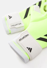 Neongula basbollhandskar med vita och svarta accenter, med präglad "PREDATOR"-logotyp och en texturerad yta för bättre grepp.