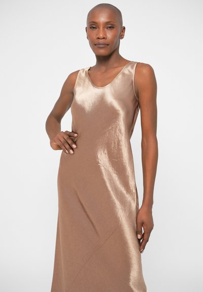 Καφέ σατέν φόρεμα χωρίς μανίκια με λεία υφή, διαθέτει λαιμόκοψη σε σχήμα σκάφους και Α-γραμμή σιλουέτα, προβάλλοντας διακριτή γυαλάδα και ρυακανδρία.