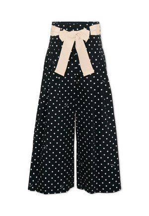 Zwarte broek met wijde pijpen, witte stippen en een beige stoffen ceintuur die in een strik aan de taille is gebonden.