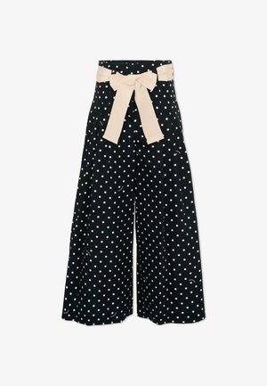 Pantaloni neri a gamba larga con pois bianchi e una cintura di tessuto beige annodata in un fiocco in vita.