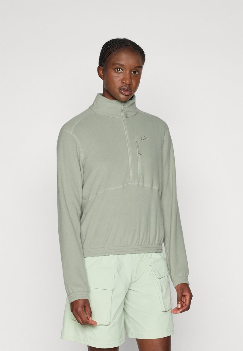Light green half-zip fleece pullover with a high collar, featuring stitched detail and a small zippered chest pocket. Paired with light green shorts.