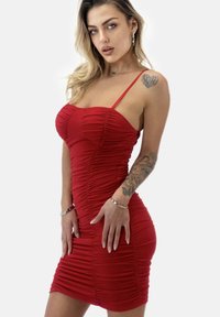 Rotes Bodycon-Kleid aus gerafftem Stoff, mit dünnen Spaghettiträgern und einer figurbetonten Silhouette. Glatte Textur und knielange Länge.