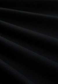 Schwarzer Stoff mit glatter Textur, der weiche, fließende Falten aufweist, die einen subtilen Glanz erzeugen. Das Material wirkt leicht und vielseitig.