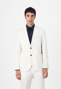 Witte katoenen blazer met notch kleppen, twee voorzakken en bruine knopen, gecombineerd met een donkerblauwe overhemdd. Slim fit ontwerp.
