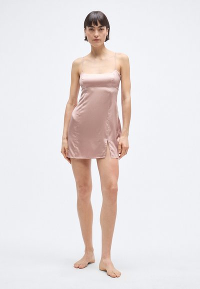 Rožinės spalvos satininė suknelė su siaurais dirželiais, kvadratine iškirpte ir šonine skeltuke, suteikiančia papildomo detalių. Lygus audinys pagerina bendrą išvaizdą.