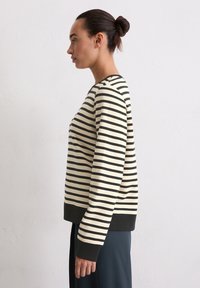 Gestreepte trui in crème en zwart. Beschikt over lange mouwen, een ronde hals en een contrasterende donkere ribbelzoom. Gladde katoenmix textuur.
