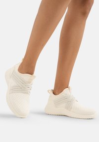 Zapatillas de malla blancas con correas cruzadas y adornos de cuentas. Presentan una suela texturizada y un diseño de tobillo alto para un ajuste seguro.