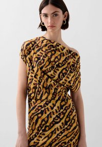 Off-shoulder kjole i gul med et sort og orange leopardmønster. Blødt, letvægtsstof med en draperet pasform og korte ærmer.