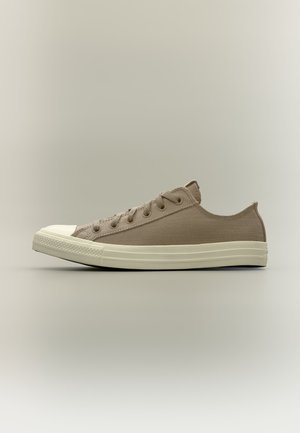 Μπεζ αθλητικό παπούτσι καμβά χαμηλού προφίλ με λευκή λαστιχένια σόλα και προστατευτική μύτη, εμφανίζεται σε πλάγια όψη σε ουδέτερο φόντο.