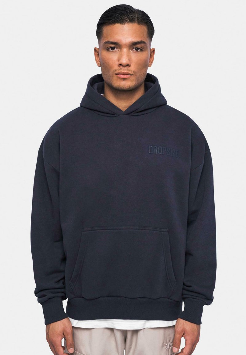 Sort hætte Sweatshirt lavet af blødt stof. Har en frontlomme og "DROPSIZE" logo i toner broderet på brystet.