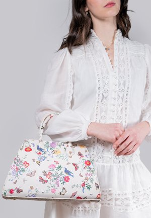 Bolso blanco con estampados de flores y mariposas; material suave; forma estructurada; doble asa y acentos de costura decorativa.