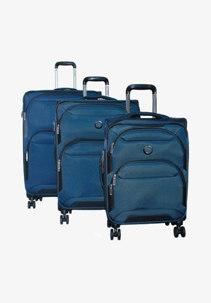 Tre valigie blu impilate, realizzate in un tessuto resistente con accenti neri, compartimenti con zip e maniglie retrattili; ciascuna con quattro ruote.