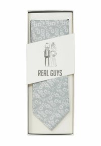 Cravate florale gris clair avec une finition texturée, emballée dans une boîte crème ornée d'illustrations noires et du texte "REAL GUYS."