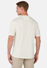 Balta trumpa rankovė t-shirt pagaminta iš lengvos medžiagos, su apvaliu iškirpimu ir mažu stačiakampiu pleistru gale.