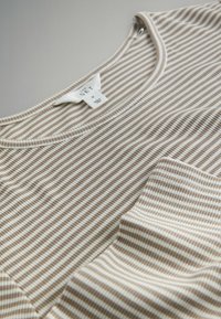 Gestreept T-shirt in beige en witte stof, met een ronde halslijn en een zakdetail. Zachte textuur, korte mouwen en een casual pasvorm.