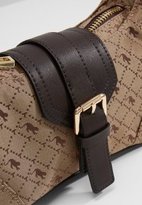 Cintura in pelle marrone con fibbia dorata su una borsa in tessuto beige decorata con piccoli profili di animali marroni.