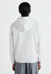 Grijze hoodie met een zachte textuur, voorzien van een grote capuchon en geribbelde boorden. Het ontwerp is casual met een ontspannen pasvorm.