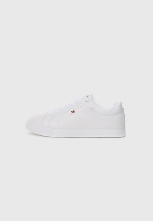 Hvid lavt sneakers med snørelukning og lille rød, hvid og blå logo på siden, på lys grå baggrund.