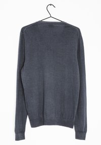 Un pull à manches longues gris foncé avec une texture lisse, un col rond et des poignets et un ourlet côtelés, exposé suspendu sur un crochet noir.