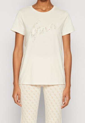 Crèmekleurig T-shirt met korte mouwen en een ronde hals met een fonkelend tekstontwerp in sierlijke letters. Zachte stof, losse pasvorm. Gecombineerd met een broek met patroon.