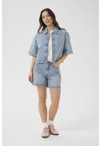 Svetlo modra jeans jakna s kratkimi rokavi, z gumbom za zapiranje, usklajeni šorti in roza športnimi copati z belimi nogavicami. Preprost in sproščen dizajn.
