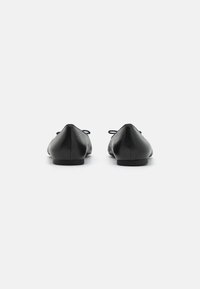 Ballerine in pelle nera con design a punta, tacco piatto e piccoli fiocchi sul retro, caratterizzate da una texture liscia e lucida.