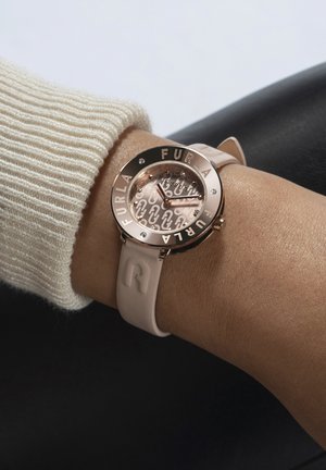 Orologio rotondo con cassa in oro rosa, cinturino in silicone rosa e quadrante decorato con il logo "FURLA" e dettagli in cristallo.