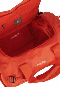 Bolsa de deporte Haglöfs roja con apertura amplia, bolsillo interior con cremallera, asas acolchadas y logotipo de la marca visible por dentro y por fuera.
