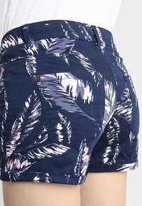 Námornické šortky s tropickým vzorem listů v růžové a bílé barvě. Vyrobené z denimu, s zadními kapsami a ohrnutým lemem.