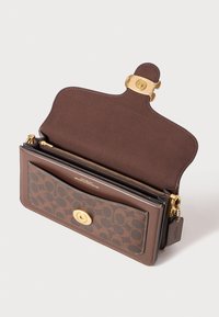 Portefeuille en cuir marron avec un fermoir à pression doré, présentant un intérieur texturé, une poche zippée et un extérieur à motifs. Comprend une étiquette suspendue.
