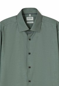 Hellgrünes Hemd aus strukturierter Baumwolle. Verfügt über eine durchgehende Knopfleiste mit dunklen Knöpfen, einen Kentkragen und ein Etikett, das Größe und Passform angibt.
