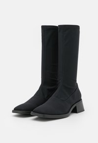 Svarta stövletter till mitten av vaden, tillverkade av texturerat material med spetsig tå och blockklack, med släta sömmar längs skaftet för extra detalj.