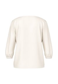 Cream-colored long-sleeve blouse with elastic cuffs, shown from the back on a plain white background.